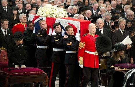 The coffin is carried as the Queen looks on