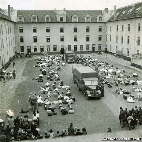 Watched by prisoners, German officers oversee piles of baggage at Kazerne Dossin