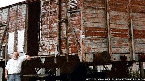 Simon Gronowksi with a cattle wagon used in the convoys to Auschwitz [Archive: Michel van der Burg / Photo: Marc Van Roosbroeck]