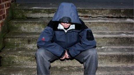 Teenager in hood sits on steps