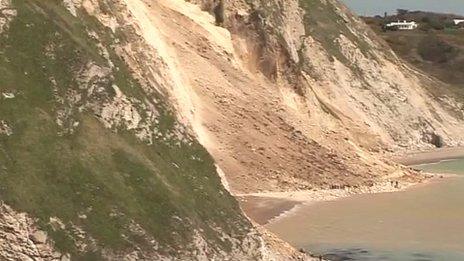 People walking along the beach below the landslip