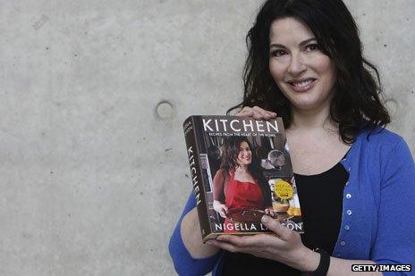 Nigella Lawson holding a copy of her 2011 book, Kitchen