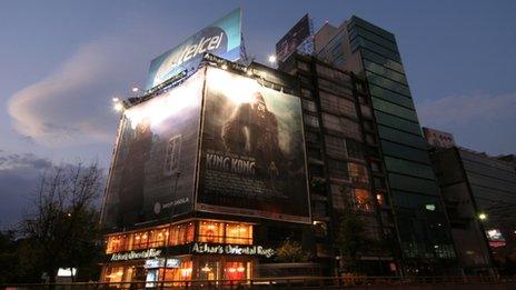 Billboard advertisement signs for Motorola, King Kong and Telcel hanging over an Oriental Rug shop in Mexico City.