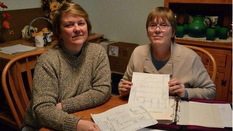 Women hold up paperwork