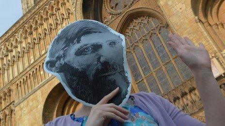 A fan in a Lawrence mask poses outside Lincoln cathedral