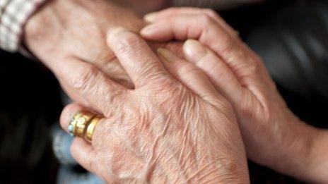 Carer holding elderly person's hand