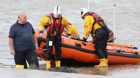 Man stuck in mud with lifeboat behind him