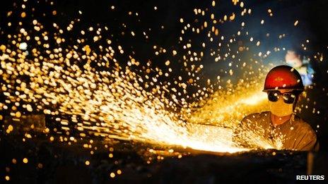 A worker wearing protective glasses welds steel products at a heavy equipment manufacturing factory in Luoyang, Henan province