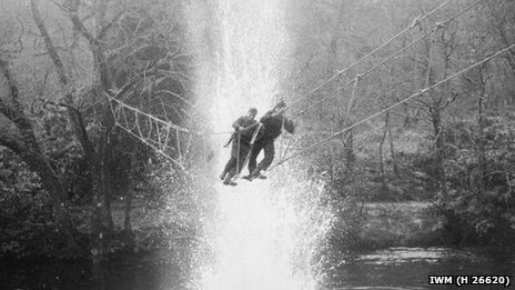 Commandos crossing a river on a toggle bridge at the training depot in Achnacarry, January 1943