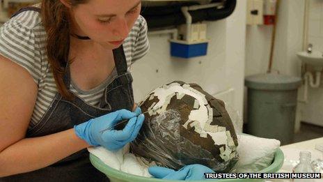 Conservator adhering fragments together of a ceramic cremation vessel