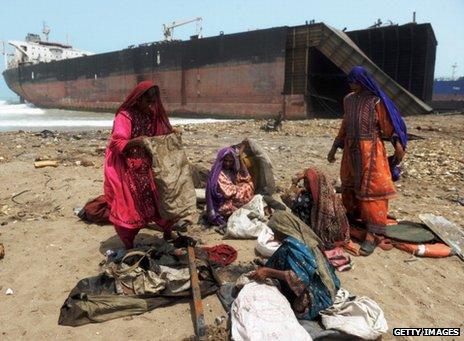 Women collect scrap metal on a beach in Pakistan