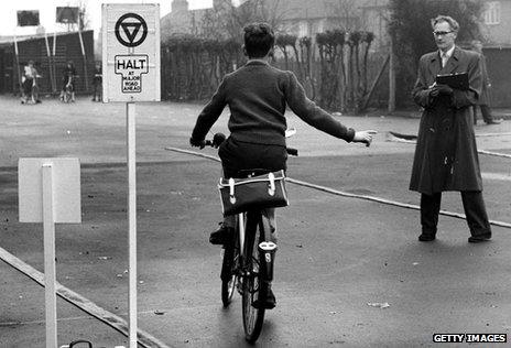 A pupil at a school in Harrow Weald, Middlesex, makes a right turn at a model halt sign during a cycling proficiency test in 1961