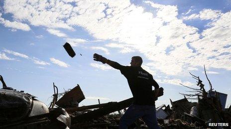 Jon Booth carries debris from his mother's tornado-destroyed home