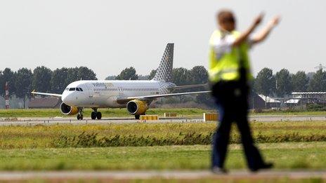 An airport worker in the taxi area at Amsterdam's Schiphol Airport, with a recently-landed plane visible in the background