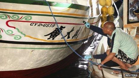 A fisherman stoops beside an investigator as they inspect the Guang Ta Hsin 28 fishing boat during an investigation of the vessel after its arrival in southern Taiwan on 11 May 2013