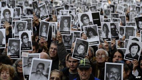 People hold portraits of victims of the terrorist bombing attack against the Argentine Israelite Mutual Association (AMIA) institute that killed 85 people and injured 300, blamed on Iran during the commemoration of its 18th anniversary, in Buenos Aires on 18 July 2012