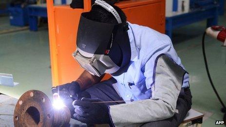 An factory worker welds at an air conditioner manufacturing facility near Ahmedabad