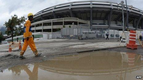 A workman walks past a large puddle outside Rio de Janeiro's Maracana football stadium