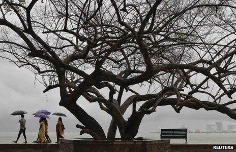 Beachgoers stroll along the Fort Kochi beach while holding umbrellas during a rain shower in the southern Indian city of Kochi May 29, 2013