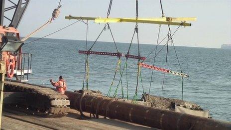 Crane operators pulling the rusted plane out of the sea