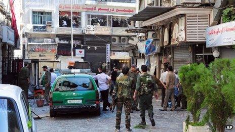 Syrian army soldiers stand guard at a scene of two explosions in the central district of Marjeh, Damascus, Syria ( Image provided by Syrian news agency SANA)