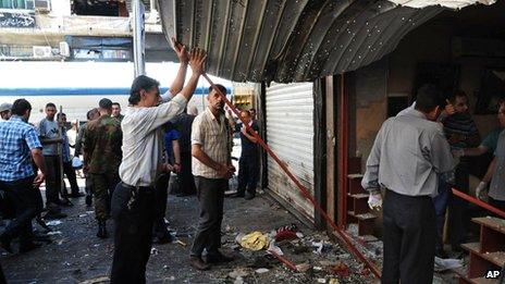 Syrians inspect damaged shops at a scene of two explosions in the central district of Marjeh, Damascus, Syria (s photo released by the Syrian official news agency SANA)