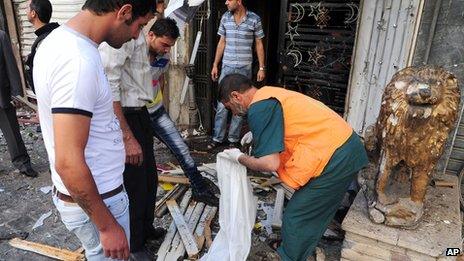 Syrians inspect damaged shops at a scene of two explosions in the central district of Marjeh, Damascus, Syria (s photo released by the Syrian official news agency SANA)