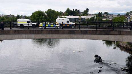 Police officers stand by their armoured vehicles on a bridge in Enniskillen