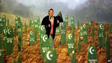 Woman walks through graves of Bosniaks reburied after being found in a mass grave, in Memici, 1999