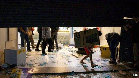 Unidentified people carry a TV set during clashes in Sao Paulo,