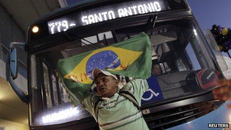 A man holding a Brazilian national flag stands in front of a bus during a protest in Brasilia