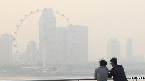 Men watch the sun set in the hazy skyline of the Singapore Flyer on 18 June 2013