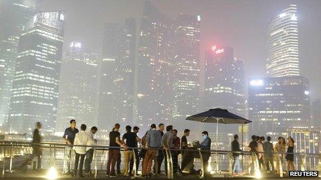 Partygoers line up to enter a nightclub at Marina Bay Sands, as haze shrouds the skyline of Singapore in the background on 19 June 2013