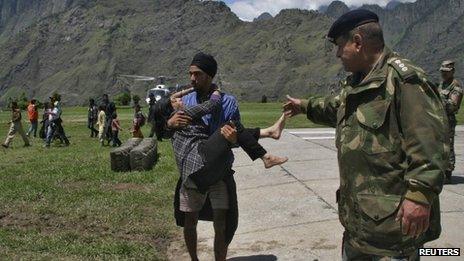 A man carries a flood victim after they were rescued by the army in Uttarakhand on June 19, 2013