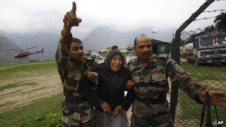 An injured pilgrim cries as army soldiers carry her after she was rescued in Uttarakhand on 24 June 2013