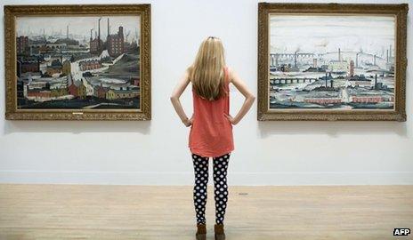 An employee poses for a picture in front of English artist Laurence Stephen Lowry"s paintings "Industrial Landscape (Ashton Under Lyne 1952) (L) and "Industrial Landscape 1955" (R) at the Lowry and the Painting of Modern Life exhibition at Tate Britain in London on June 24, 2013.