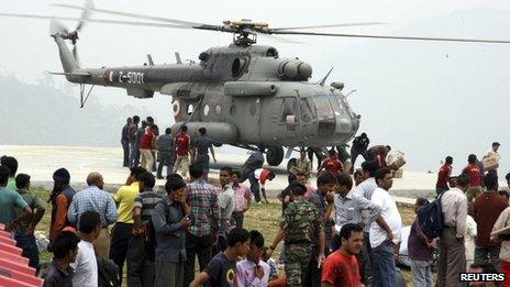 Personnel from the Indian armed forces carry relief supplies from a helicopter for the stranded people at Guptkashi