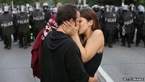 A couple kiss in front of police at a G8 summit protest