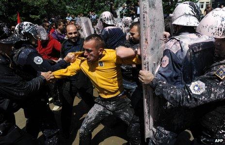 Paint-spattered Kosovan police struggle with a protester in Pristina, 27 June