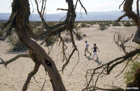 Tourists walk in the Mesquite Dunes as temperatures approach record levels in Death Valley National Park, California, on Saturday