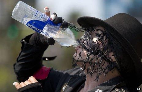 Michael Jackson impersonator Juan Carlos Gomez drinks some water as he takes a break from posing for photos with tourists along The Strip in Las Vegas on Friday