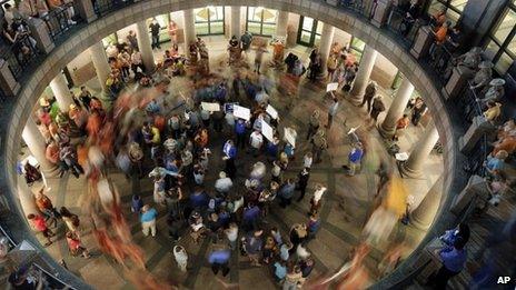 Opponents of an abortion bill walk in circles around supporters of the bill as a committee holds hearings on the bill near by at the Texas state capitol, 2 July 2013