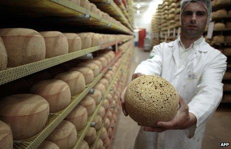 A cheesemonger holds a 24-month old mimolette cheese at a production site in Isigny-sur-Mere, north-western France, 4 July