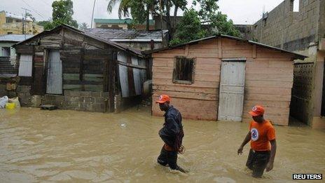 Men walk through floodwaters caused by Tropical Storm Chantal in Santo Domingo, capital of the Dominican Republic (10 July 2013)