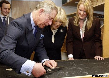 Prince Charles cutting a shape out of some material at tailor company Gieves & Hawkes