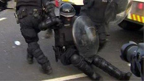 Police officers drag an injured colleague to safety