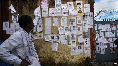 A man looks at a wall covered with pictures of missing people near the airport in northern Indian state of Uttarakhand on June 26, 2013