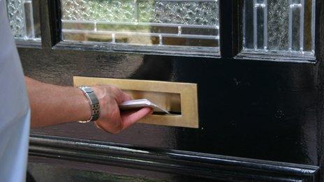 Postman putting letters through a letter-box