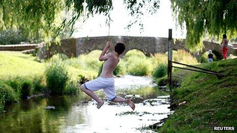 A boy swings across a stream in Anstey, England