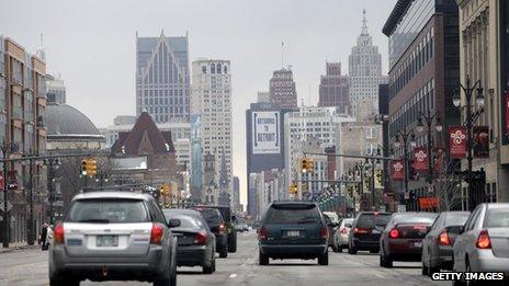 Cars in downtown Detroit in February 2013, with a sign on a skyscraper saying 'Outsource to Detroit'.